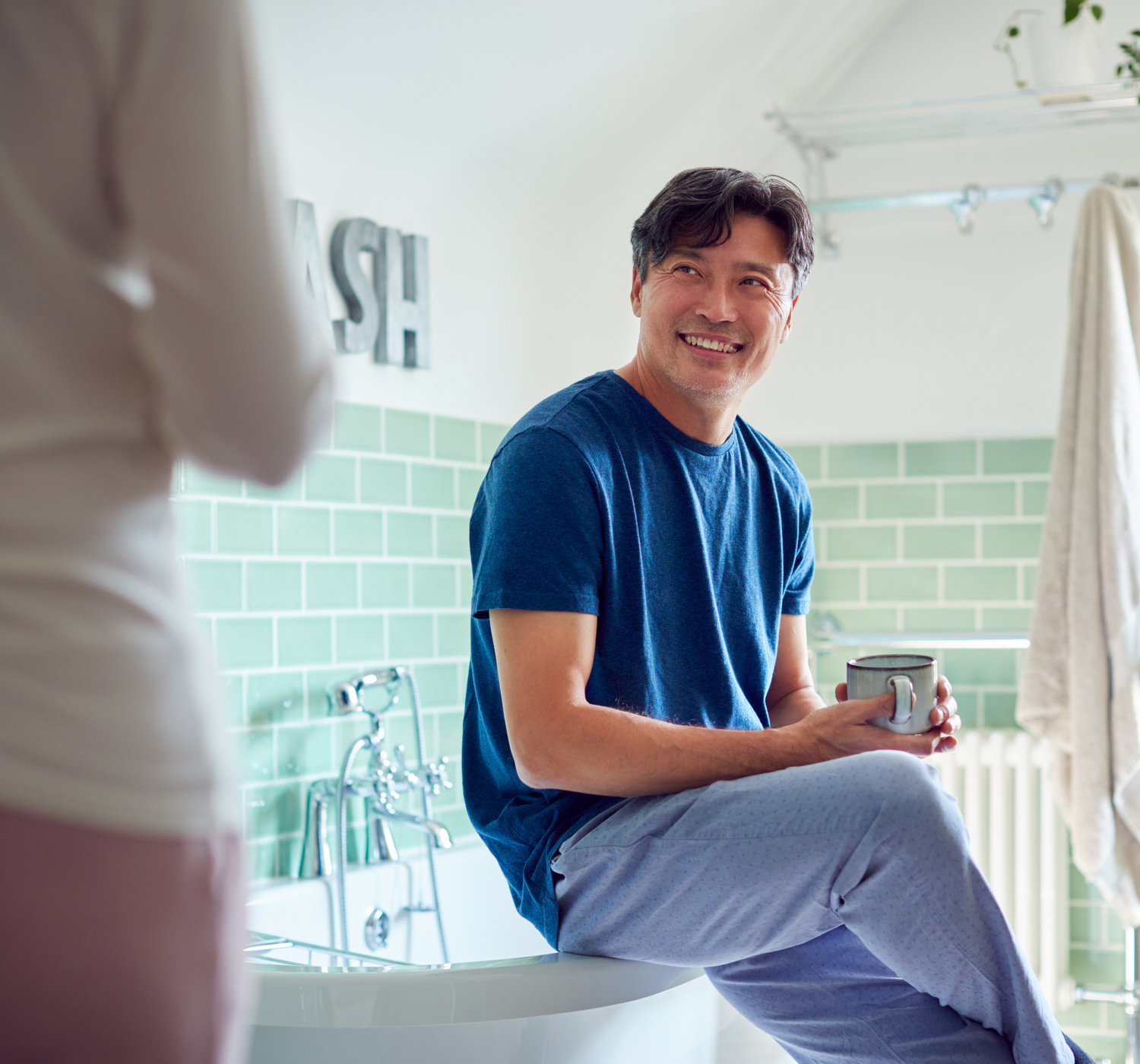 Mature Asian Couple Wearing Pyjamas Sitting In Bathroom Enjoying Morning Hot Drinks Together